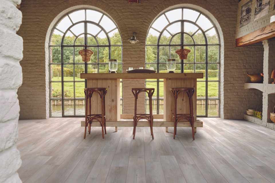 Wood look luxury vinyl in kitchen with open arch windows and natural wood, exposed brick, and beams